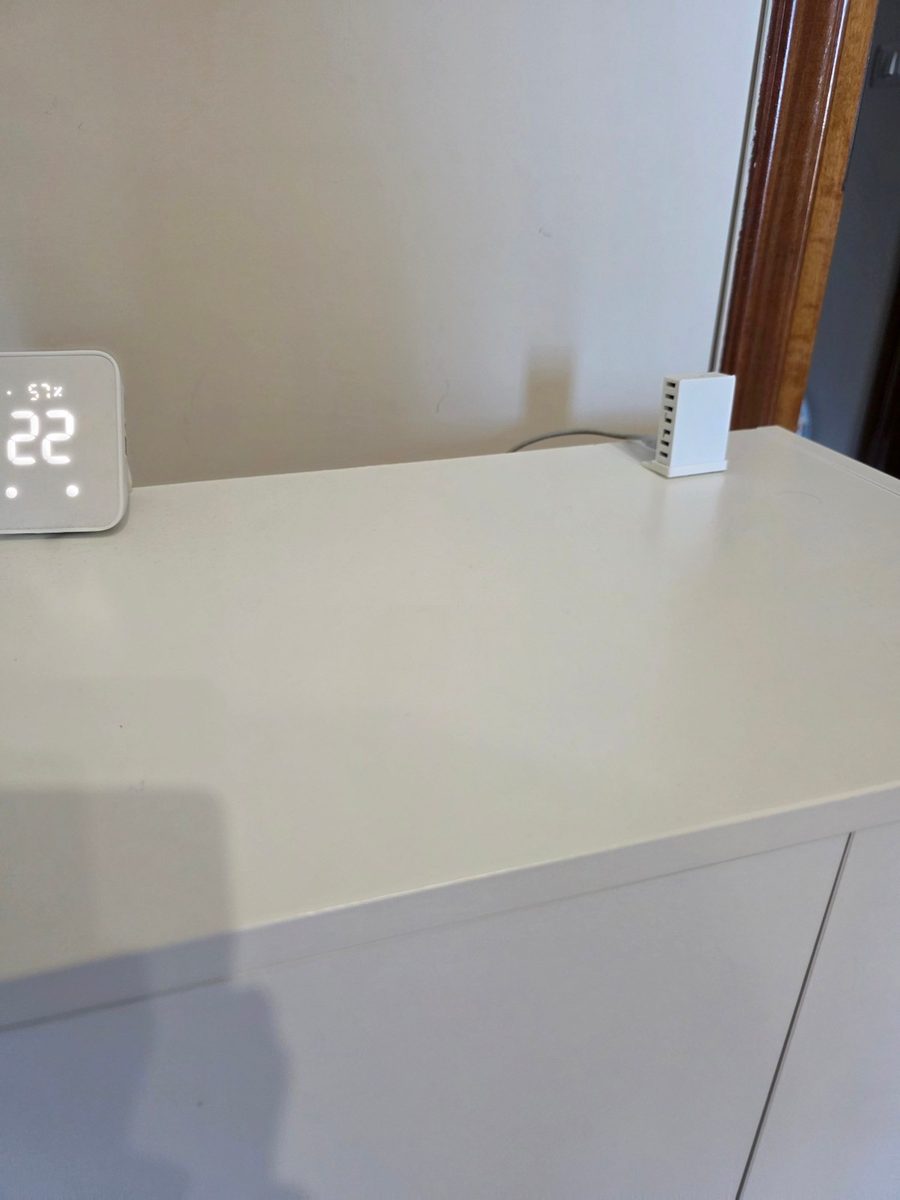 MTR-1 su un mobile bianco accanto a un termometro SwitchBot che segna 22 gradi e 57 per cento