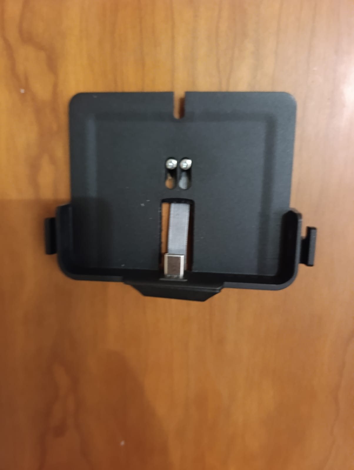 Staffa nera dell'EZVIZ CP4 fissata alla porta con due viti, con il cavo piatto e il connettore che escono dal foro