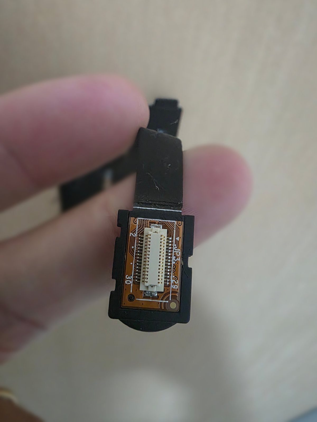 Connettore a pettine all'estremità del cavo piatto dell'EZVIZ DP1C tenuto tra due dita