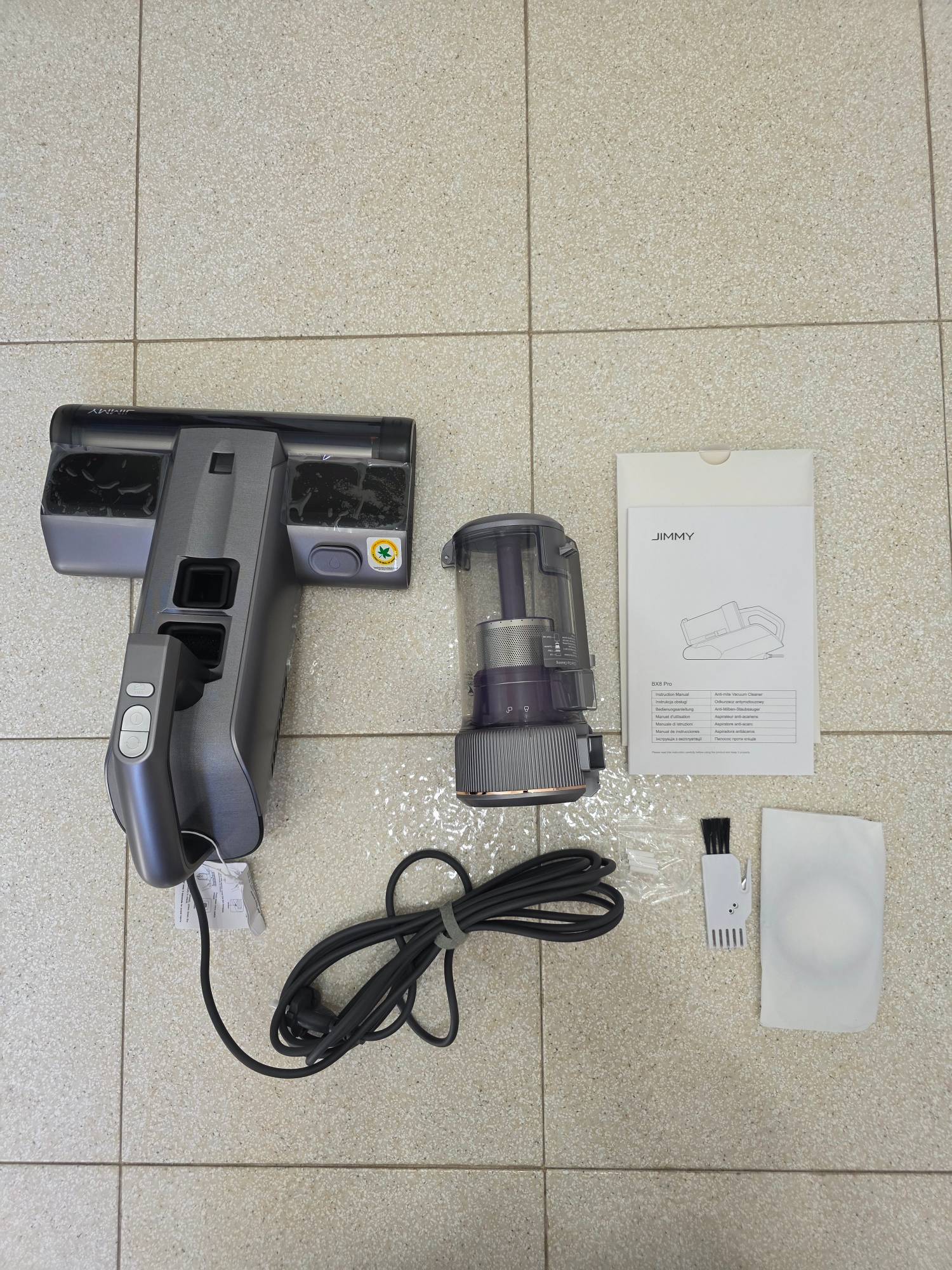 Contenuto della confezione del JIMMY BX8 Pro disposto sul pavimento: corpo macchina, contenitore, cavo, manuale e accessori