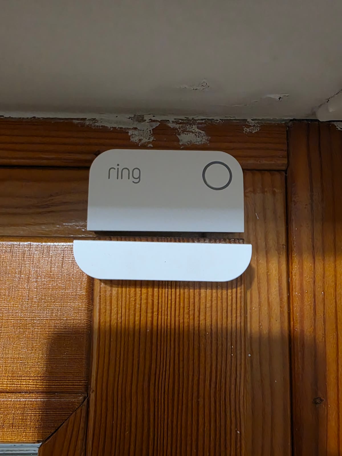 Primo piano di un sensore di contatto Ring Alarm e del suo magnete su un infisso in legno