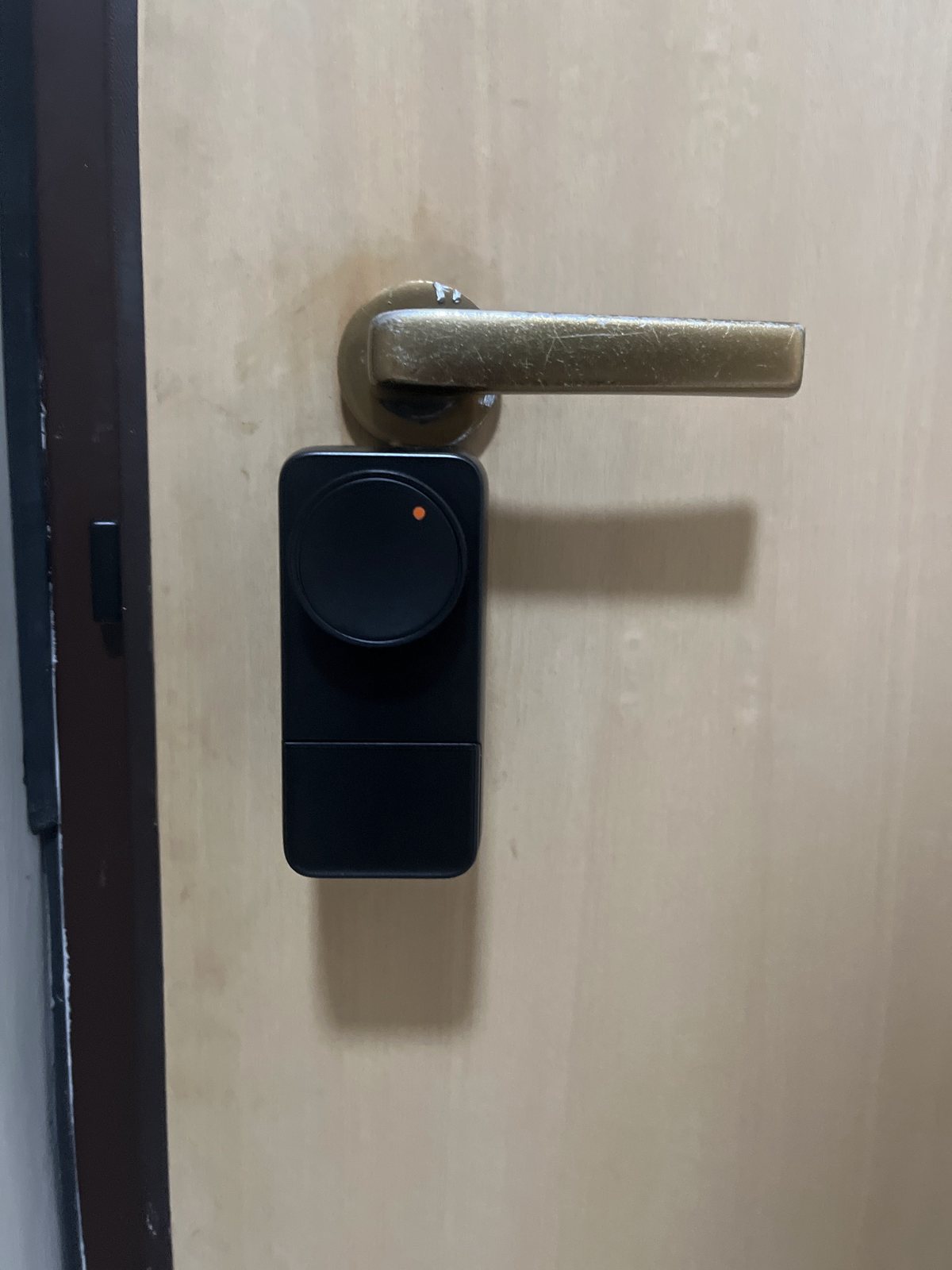 SwitchBot Lock Pro nera con pomolo rotondo e punto arancione montata sotto la maniglia