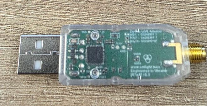 Primo piano della chiavetta SLZB-07p7: scheda verde con il chip quadrato al centro e il connettore dorato per l'antenna